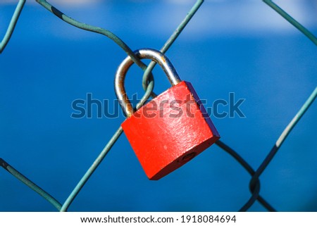 Red padlock in a metal fence