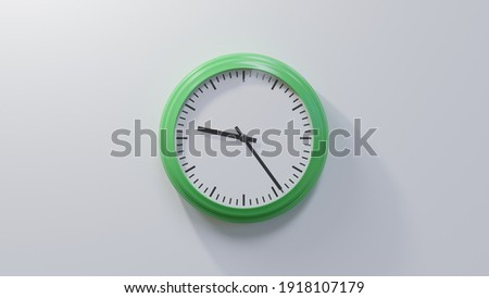 Glossy green clock on a white wall at twenty-four past nine. Time is 09:24 or 21:24 Royalty-Free Stock Photo #1918107179