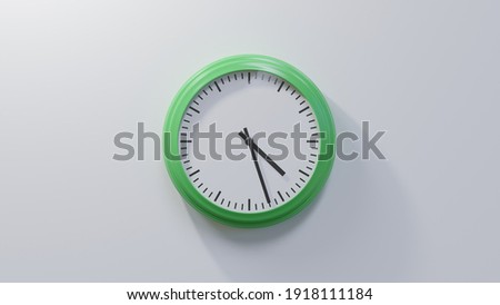 Glossy green clock on a white wall at twenty-seven past four. Time is 04:27 or 16:27 Royalty-Free Stock Photo #1918111184