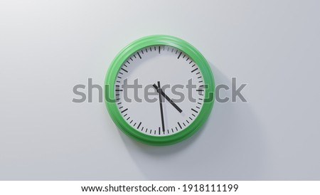 Glossy green clock on a white wall at twenty-nine past four. Time is 04:29 or 16:29 Royalty-Free Stock Photo #1918111199