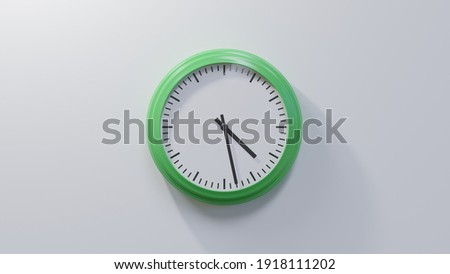 Glossy green clock on a white wall at twenty-eight past four. Time is 04:28 or 16:28 Royalty-Free Stock Photo #1918111202