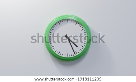 Glossy green clock on a white wall at twenty-six past four. Time is 04:26 or 16:26 Royalty-Free Stock Photo #1918111205