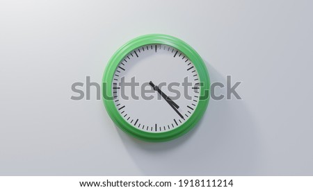 Glossy green clock on a white wall at twenty-three past four. Time is 04:23 or 16:23 Royalty-Free Stock Photo #1918111214