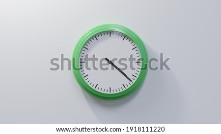 Glossy green clock on a white wall at twenty-two past four. Time is 04:22 or 16:22 Royalty-Free Stock Photo #1918111220