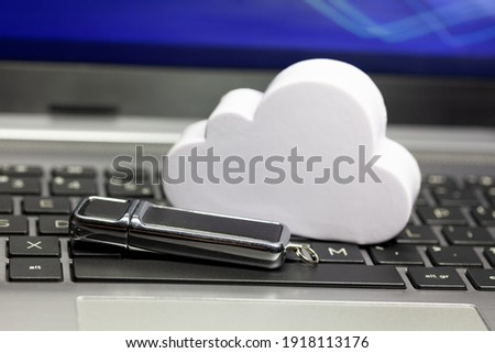 Cloud data storage technology, storing data in the cloud abstract. Cloud and a usb memory stick, pen drive laying on a laptop keyboard. Online private personal data backup service tech simple concept Royalty-Free Stock Photo #1918113176