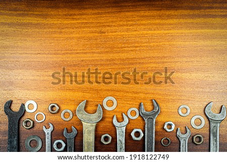 Noling style photo - Different wrenches, nuts and washers on brown wood texture background