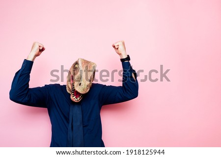 Euphoric man with dinosaur head with raised fists