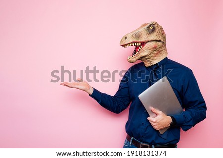 Euphoric man with dinosaur head using laptop