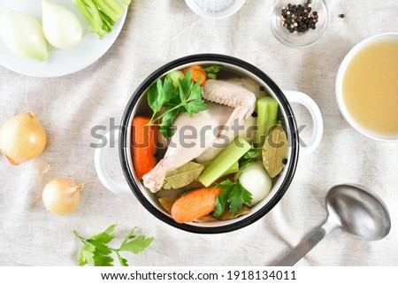 Chicken broth with vegetables and spices on light background. Healthy diet dish for dinner. Top view, flat lay 
