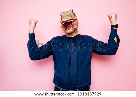 Euphoric man with dinosaur head with raised fists