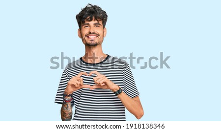 Young hispanic man wearing casual clothes smiling in love showing heart symbol and shape with hands. romantic concept. 
