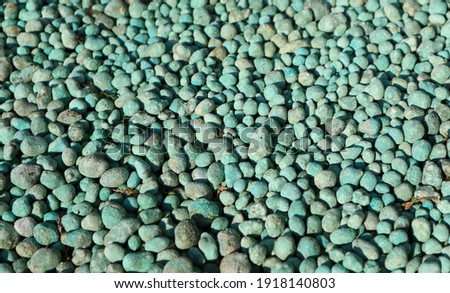 Decorative gravel of green pebbles used in garden or backyard around the plants. Background and texture
