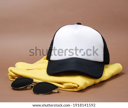 Blank baseball caps are used for design mockups. The hat on the side of an old camera and sunglasses. Plain hat isolated on brown background. Take a picture of a hat ready to be displayed. Mockup hat.