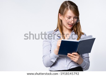 Portrait of beautiful young teacher looking into book on gray background, side space for text. High quality photo