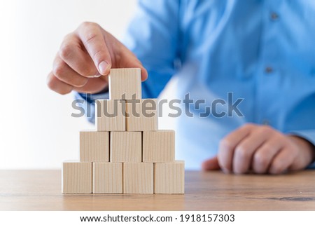 Businessman hand arranging wood blocks in a step stair concept.  Concept for growth, strategy, success process or investment goals.