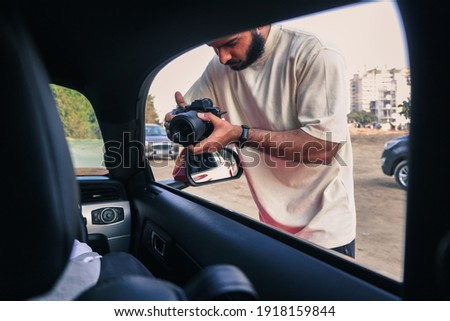 man with beard holding a camera in hand shooting video , wearing yellow tshirt  