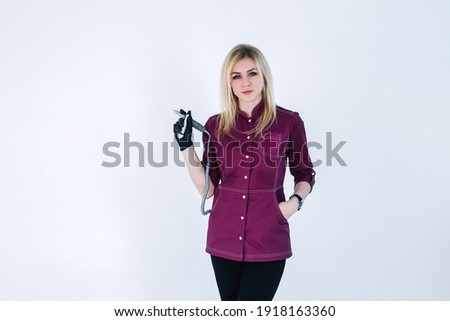 
Slender young blonde girl master of manicure in black mask
A girl with long hair in a pink uniform, a manicure master in a protective black mask from the covid virus with tools for processing nails