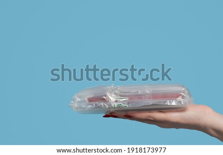 Closeup view color stock photography of female hand holding her online order wrapped properly in protective plastic air package for shipping safely fragile goods