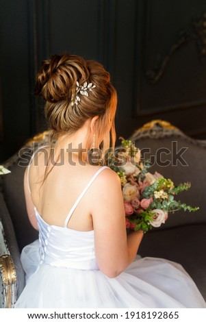 The bride from the back holds a bouquet of flowers in her hands.