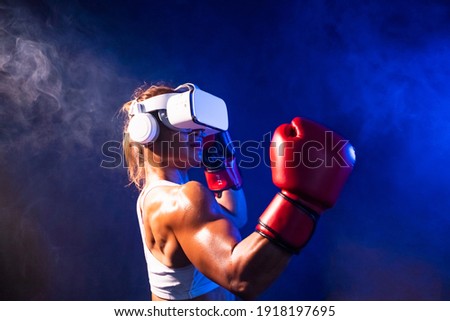 
Asian woman with tan skin and dark hair, wearing virtual reality headset and boxing gloves , training boxing with online partner, dark background, virtual sport concept