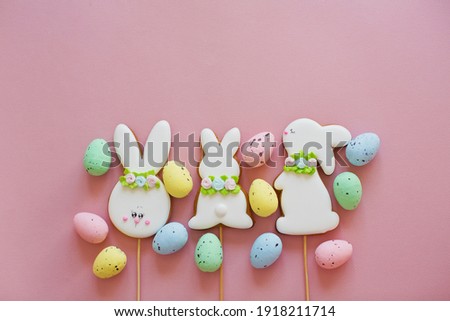 Easter glazed cookies and colorful eggs on a pink background