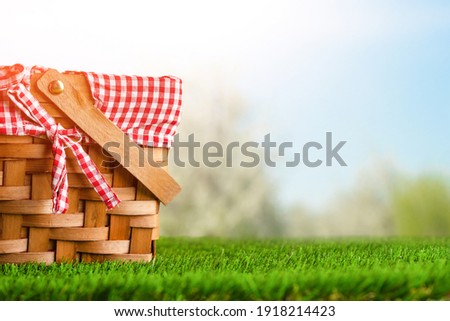 Picnic basket on the grass on the background of nature. Relaxation and summer mood. Departure for a picnic for the weekend or vacation. Royalty-Free Stock Photo #1918214423