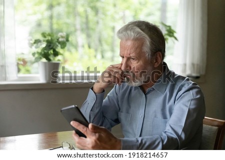 Close up stressed unhappy mature man looking at phone screen, reading bad unpleasant news in email or social network message, frustrated elderly male received debt notification, problem with device Royalty-Free Stock Photo #1918214657