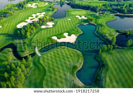Aerial view of green grass and trees on a golf field. Royalty-Free Stock Photo #1918217258