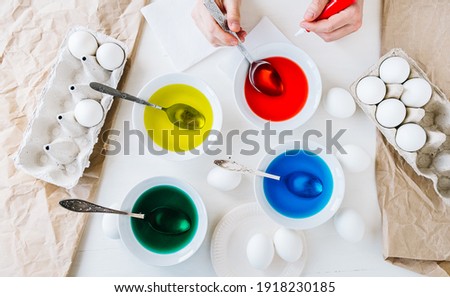 Flat lay. Dyeing Easter eggs with liquid food coloring. Different colors in different bowls
