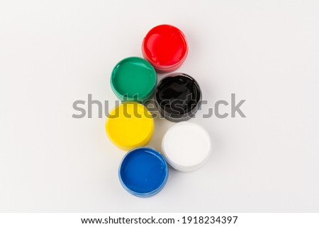 Plastic jars with paint of different colors for children's creativity on white background. Materials for drawing, creativity, early childhood development.