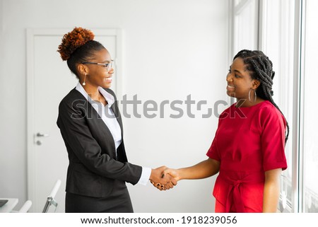 two beautiful young african women in the office shaking hands  Royalty-Free Stock Photo #1918239056