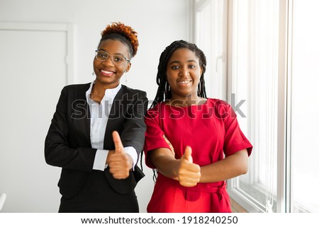 two beautiful young african women in office with hand gesture 