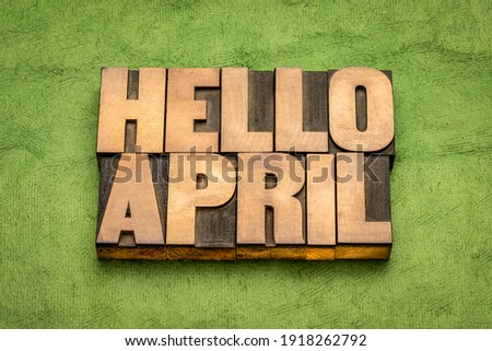 Hello April word abstract in vintage letterpress wood type against green handmade paper, cheerful greetings