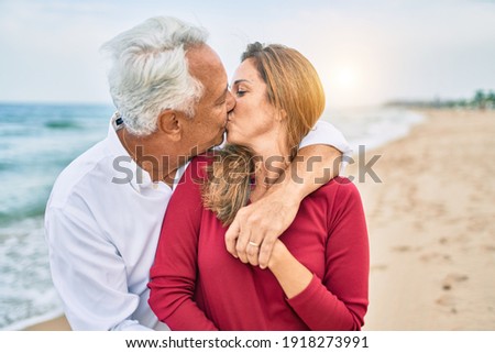 Middle age hispanic couple kissing and hugging at the beach
