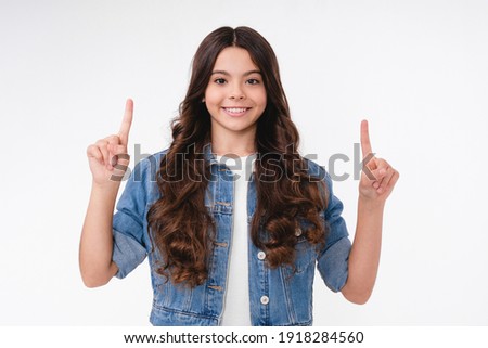 Charming white teen girl pointing at copy space isolated over white background