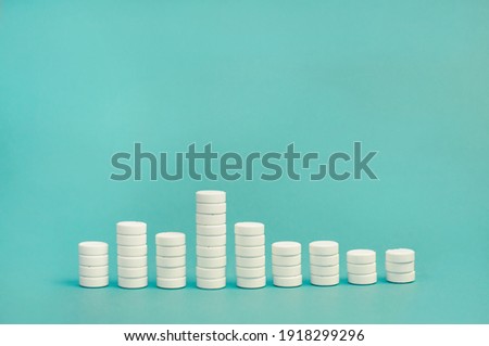 stacks of white pills on a blue background in the form of a bar chart Royalty-Free Stock Photo #1918299296
