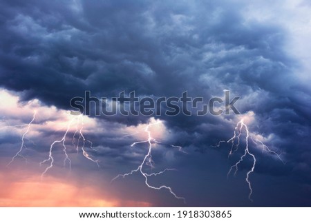 A terrible dangerous storm with a strong wind swirls thunderclouds in the mountains with fabulous twists, from which rain and hail or a thunderstorm with lightning flies. Royalty-Free Stock Photo #1918303865
