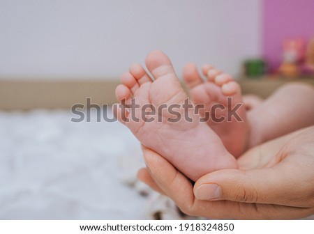 Loving mother holds the legs of a small child in the palm of his hand close-up. Woman's happiness. Photography, concept. Royalty-Free Stock Photo #1918324850