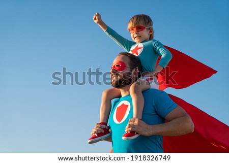 Family of superheroes having fun outdoor. Father and son playing against blue summer sky background. Imagination and freedom concept Royalty-Free Stock Photo #1918326749