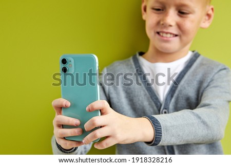 teen boy make selfie, take photo on smartphone, focus on mobile phone in hands. isolated green background