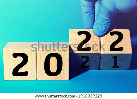 hand wearing a glove changing the year to 2022 with wooden cubes. Concept of new year with Corona Virus