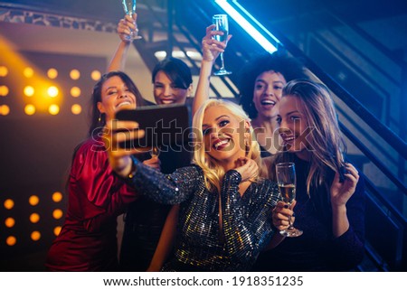 Young cheerful females taking a selfie together in a nightclub Royalty-Free Stock Photo #1918351235