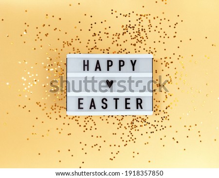 Happy Easter greeting on light box and confetti on yellow background.