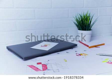 Creative workplace of a Graphic Designer with laptop. Development of a logo for the company. Drawings and sketches on paper in a art studio office