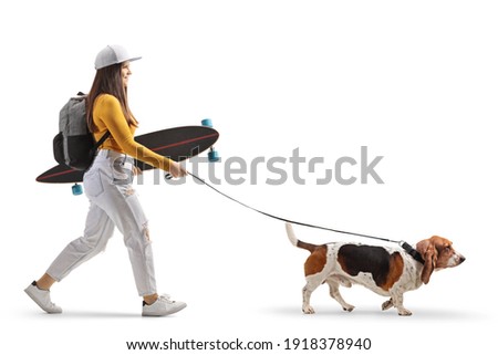 Hipster girl with a skateboard and a beagle dog on a lead isolated on white background