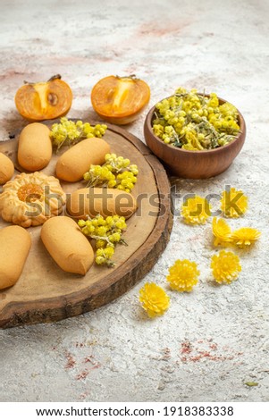 hal right side of cookies on wooden plate and a bowl of yellow flowers and palms of marble ground