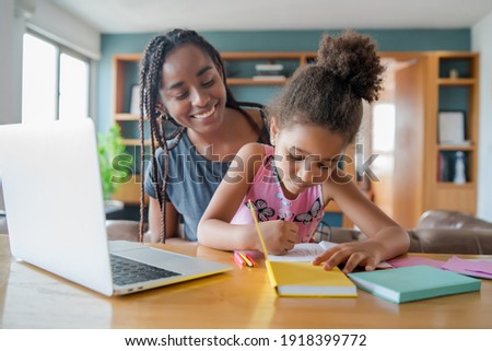 A mother helping her daughter with homeschool. Royalty-Free Stock Photo #1918399772