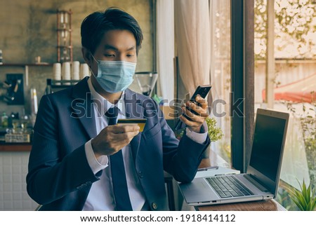 Front Right Asian Businessman in Suit Wear Face Mask Using Smartphone for Online Shopping in Coffee Shop. Asian Businessman Work from Anywhere in Covid 19 Situation in Vintage Tone