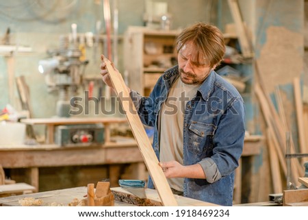 Man looking and choosing wood or testing wood plank in the carpentry shop 