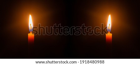 Two lit candles with lit candles in the background
